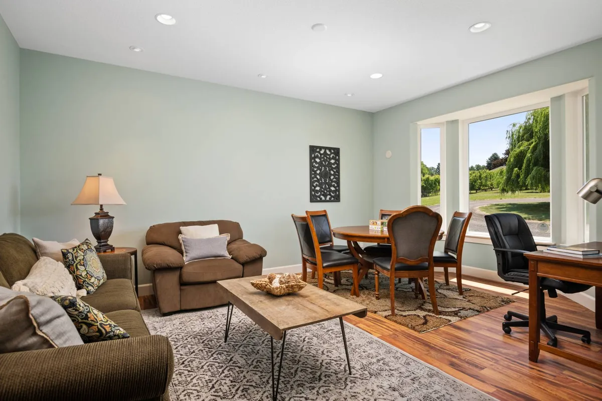 A warm, inviting living and dining space is framed by expansive windows that open up to sweeping views of the outdoor landscape. The comfortable sofa and dining table are positioned to enjoy the sunlight and scenery, blurring the line between indoor relaxation and outdoor adventure.