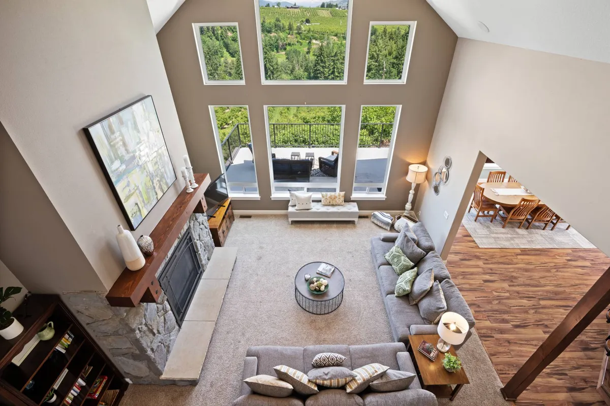 A cozy seating area centered around a fireplace, surrounded by large windows that offer sweeping views of the Oregon landscape. The arrangement exudes comfort and serenity, with natural light streaming in and outdoor vistas on display.