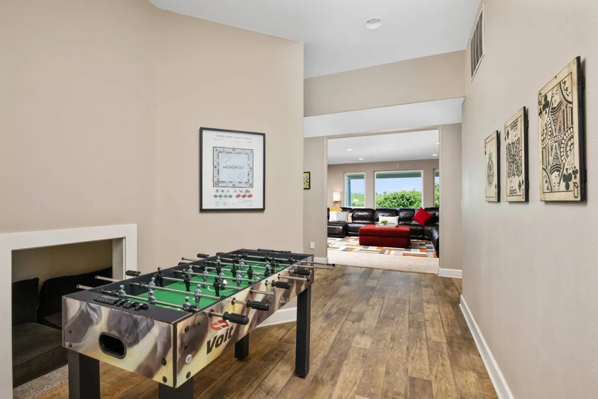 This playful and inviting image spotlights a foosball table, set in a bright and welcoming corner of the home. Framed wall art and visible living room details contribute to a cheerful, social environment ideal for game nights and family tournaments.